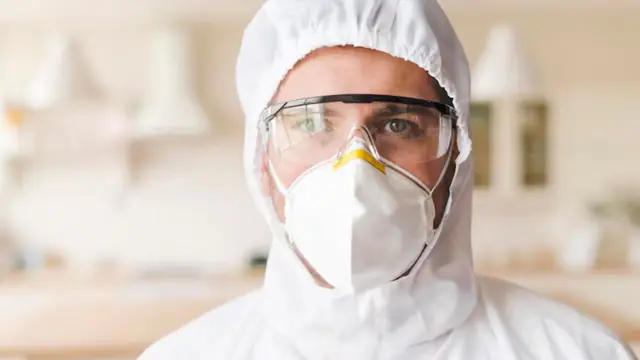 Mold remediation worker in a protective hood, goggles and respirator