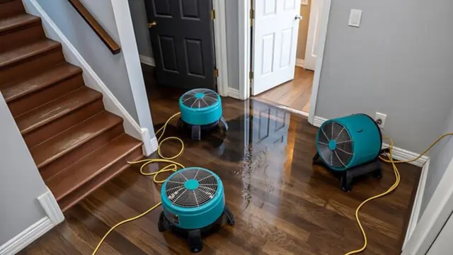 Air movers drying a wet wood floor beside a staircase